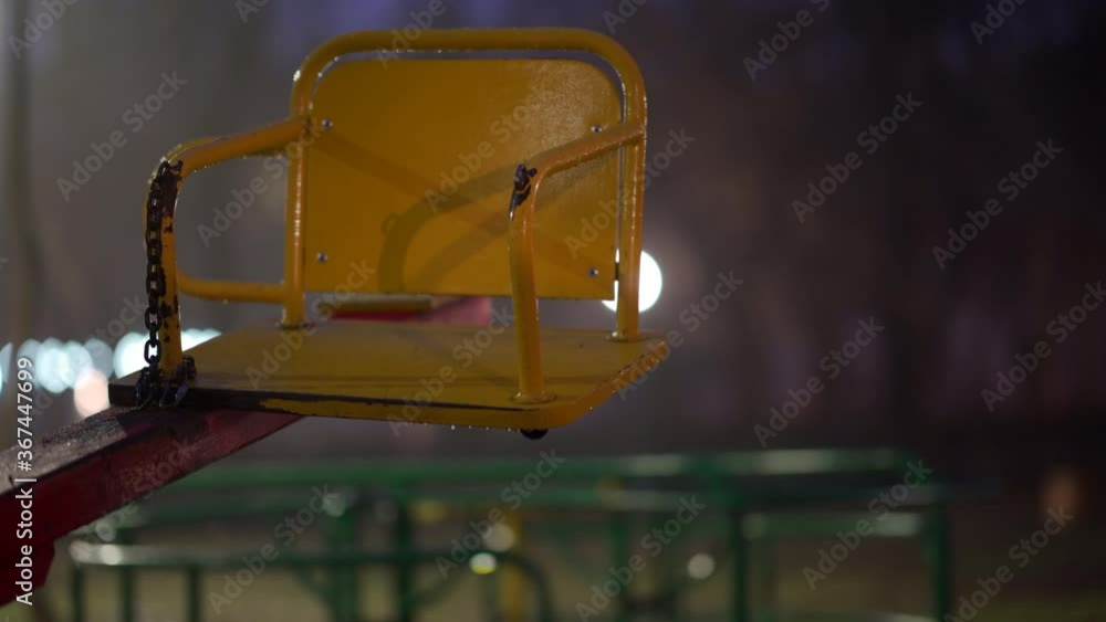 Wet swing at empty children's playground in city park on an autumn night. Wet swing at empty children's playground in city park on an autumn night.