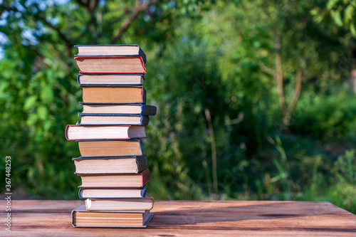 Stack of books on wooden table over nature background  outdoors