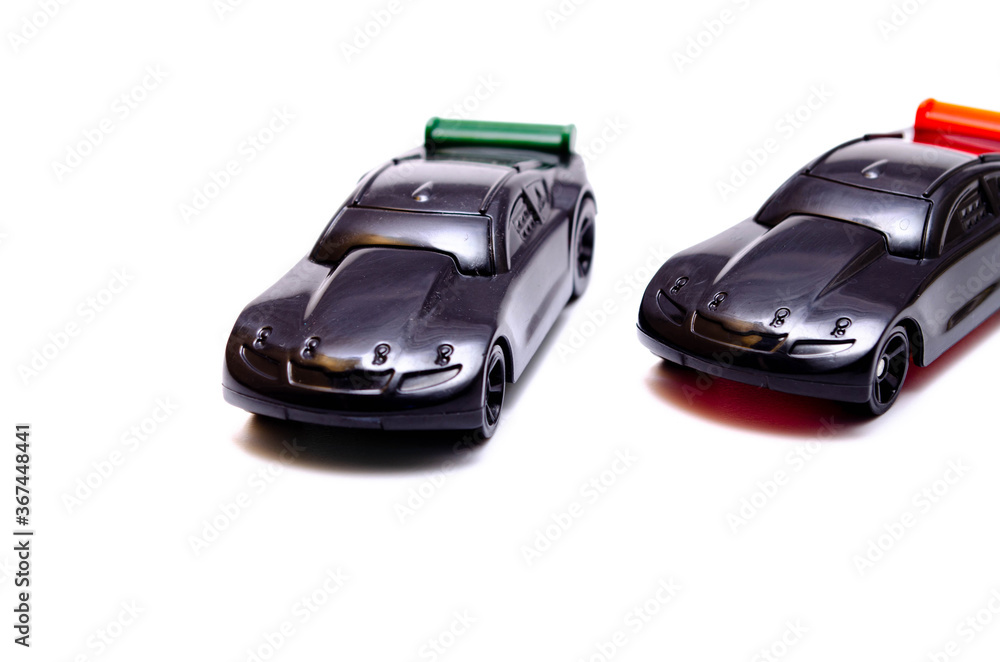 Two sports toy cars on a white background in black with a green and red wing in close-up Two sports toy cars on a white background in black with a green and red wing in close-up