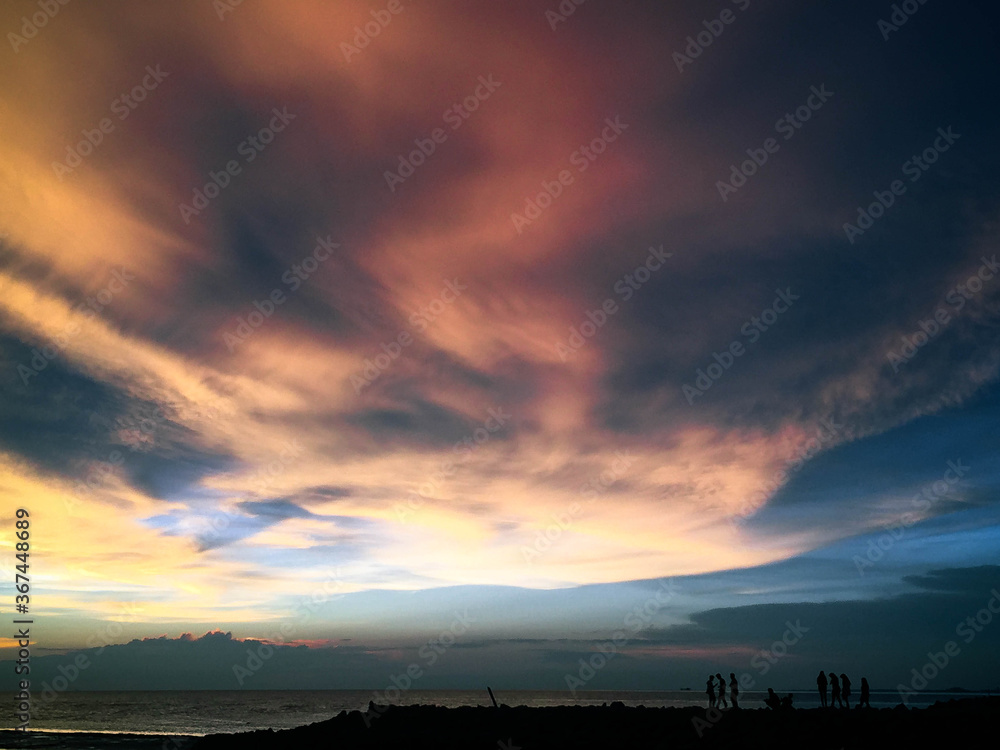 Beautiful beach sunset and many figures in the distance with amazing sky Beautiful beach sunset and many figures in the distance with amazing sky