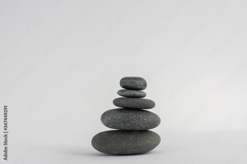 One simplicity stones cairn isolated on white background, group of five black pebbles in tower One simplicity stones cairn isolated on white background, group of five black pebbles in tower