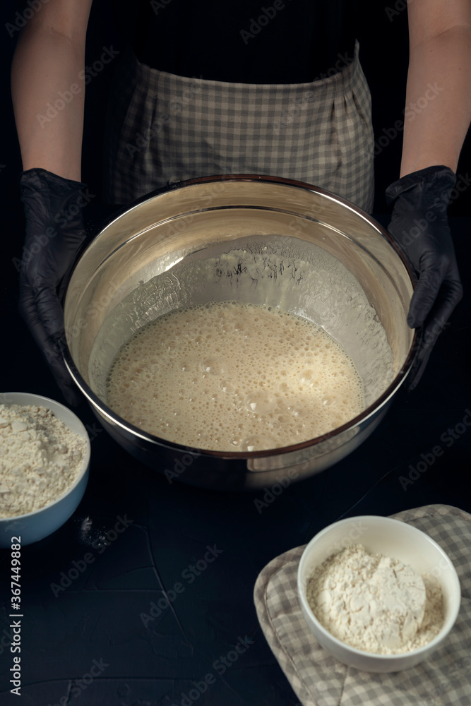 Woman in checkered apron hold bowl with liquid yeast dough. Process of making bakery. Adjarian Khachapuri Recipe – Georgian cheese bread. Woman in checkered apron hold bowl with liquid yeast dough. Process of making bakery. Adjarian Khachapuri Recipe – Georgian cheese bread.