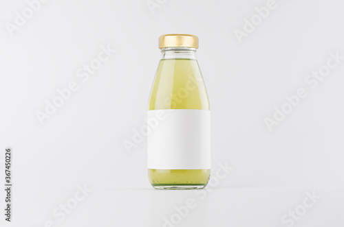 Green fruit juice in glass bottle with gold cap and white blank label mock up on white background with copy space, template for packaging, advertising, design product, branding.