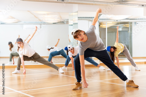 Positive teenage girls and boys training hip hop in dance studio, dance classes for teens