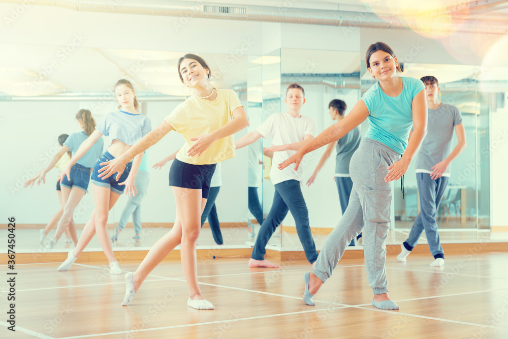 Positive teenagers are dancing hip hop in dance studio