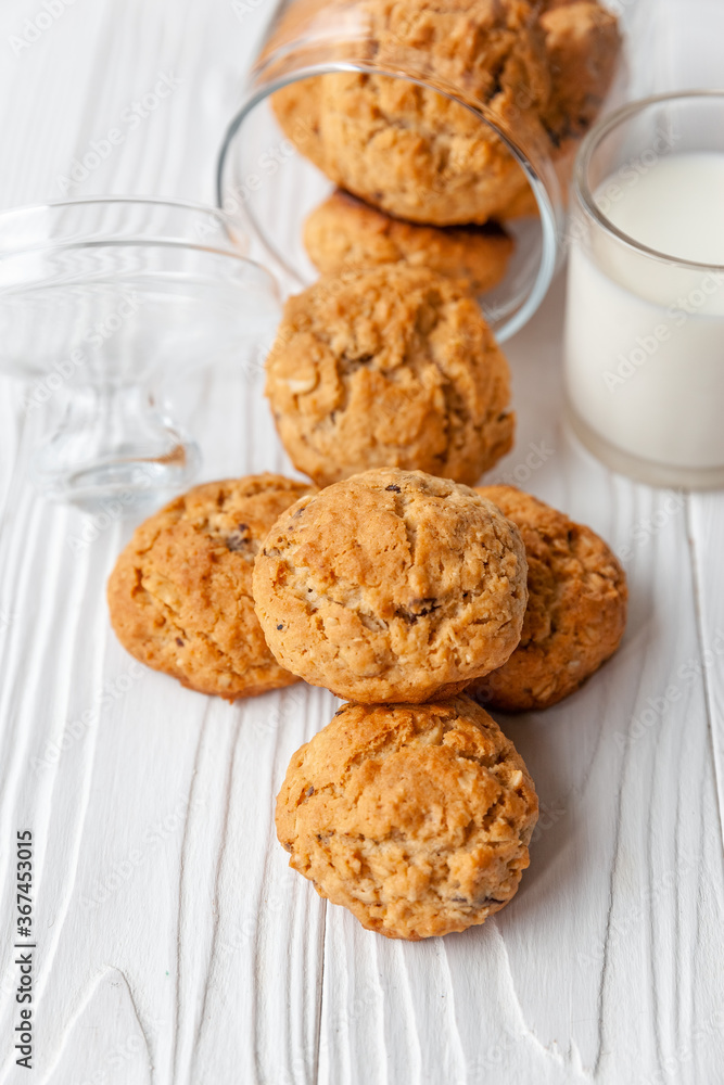Homemade oatmeal cookies on white wooden table with milk on background Homemade oatmeal cookies on white wooden table with milk on background