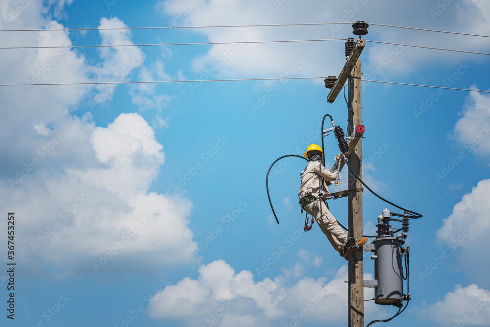 Lineman climb concrete pole are installing hotline-clamps to the ends of  insulated electrical cables. To prepare for the installation of a single  phase transformer into a high voltage distribution. Photos