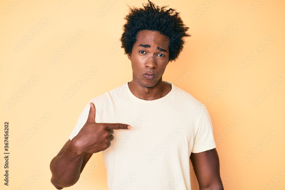 Handsome african american man with afro hair pointing with fingers to himself skeptic and nervous, frowning upset because of problem. negative person. Handsome african american man with afro hair pointing with fingers to himself skeptic and nervous, frowning upset because of problem. negative person.