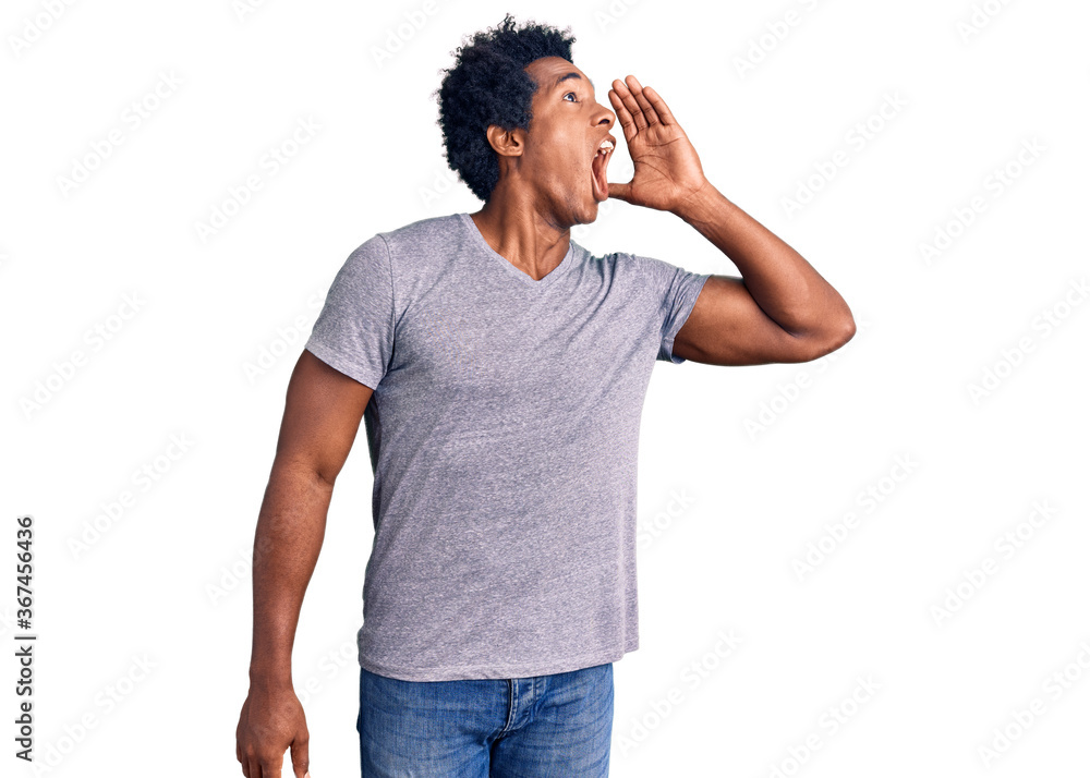 Handsome african american man with afro hair wearing casual clothes shouting and screaming loud to side with hand on mouth. communication concept. Handsome african american man with afro hair wearing casual clothes shouting and screaming loud to side with hand on mouth. communication concept.