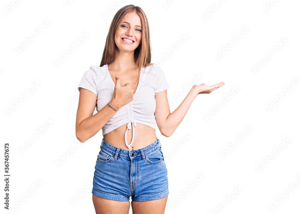 Young beautiful blonde woman wearing casual white tshirt showing palm hand and doing ok gesture with thumbs up, smiling happy and cheerful Young beautiful blonde woman wearing casual white tshirt showing palm hand and doing ok gesture with thumbs up, smiling happy and cheerful