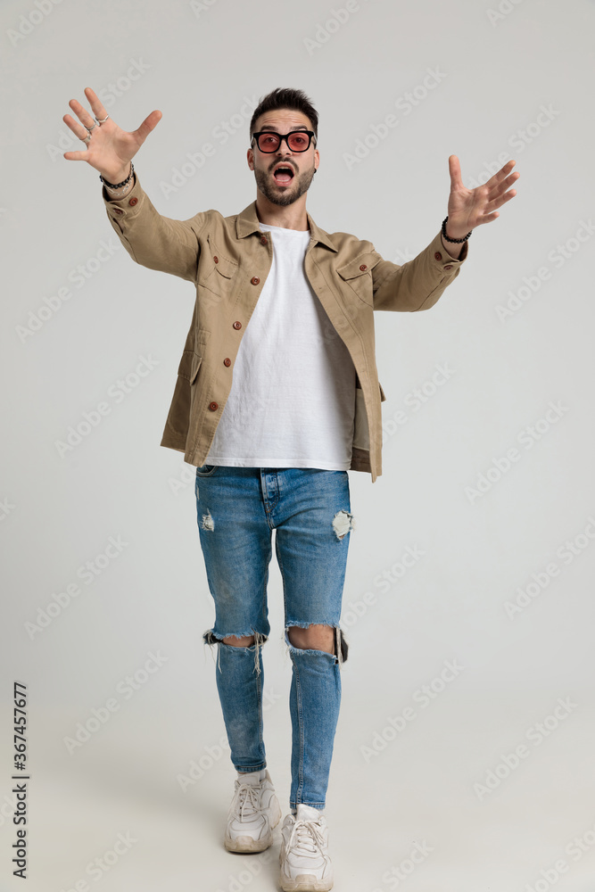 young casual man in jacket wearing holding hands in a catching position - obrazy, fototapety, plakaty 