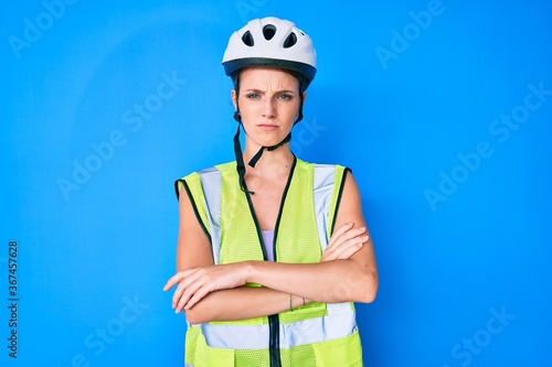 Young caucasian girl wearing bike helmet and reflective vest skeptic and nervous, disapproving expression on face with crossed arms. negative person.