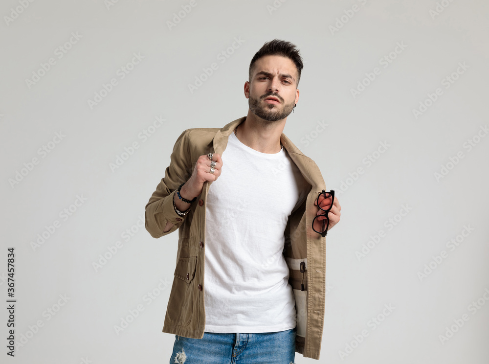 young casual man holding sunglasses and adjusting jacket young casual man holding sunglasses and adjusting jacket
