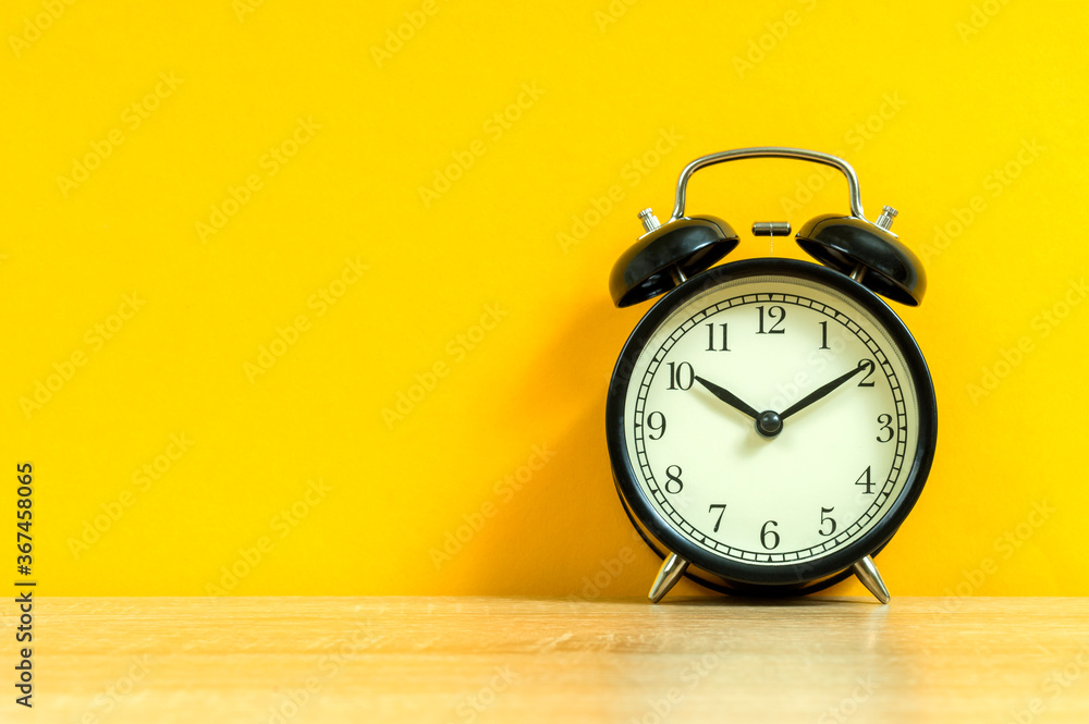 black alarm clock on a yellow background, business concept black alarm clock on a yellow background, business concept