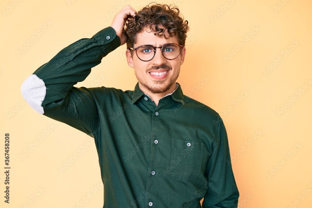 Young caucasian man with curly hair wearing casual clothes and glasses confuse and wonder about question. uncertain with doubt, thinking with hand on head. pensive concept. Young caucasian man with curly hair wearing casual clothes and glasses confuse and wonder about question. uncertain with doubt, thinking with hand on head. pensive concept.