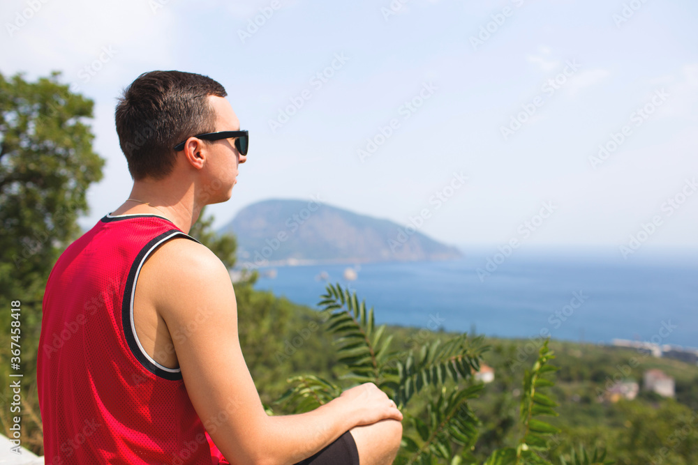 Happy man traveler sitting on mountain alone and looking at the sea. Photos for ads and billboards. 