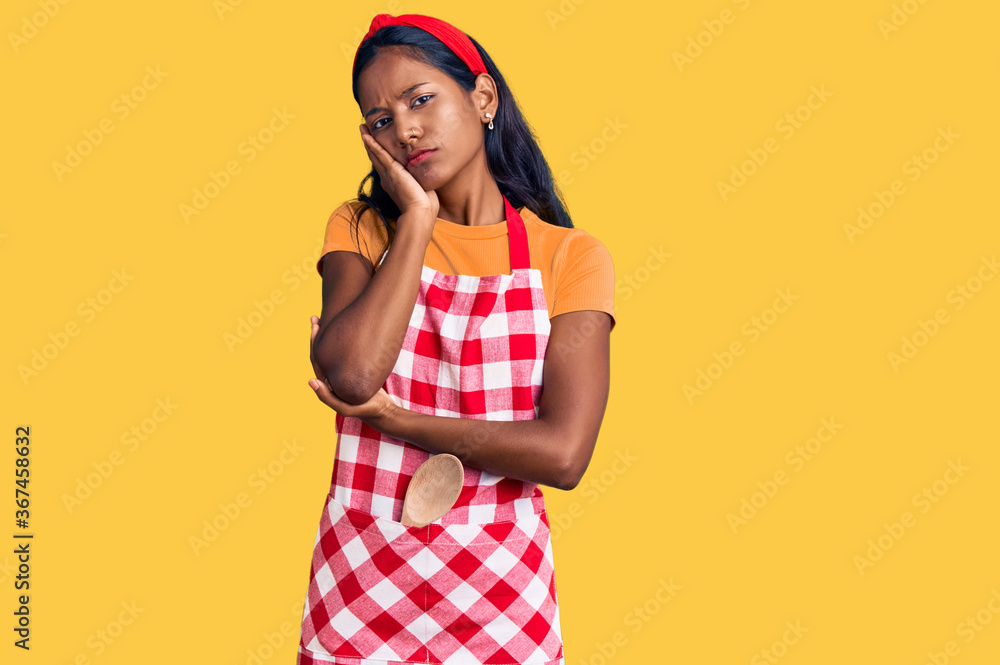 Young indian girl wearing professional baker apron thinking looking tired and bored with depression problems with crossed arms. Young indian girl wearing professional baker apron thinking looking tired and bored with depression problems with crossed arms.