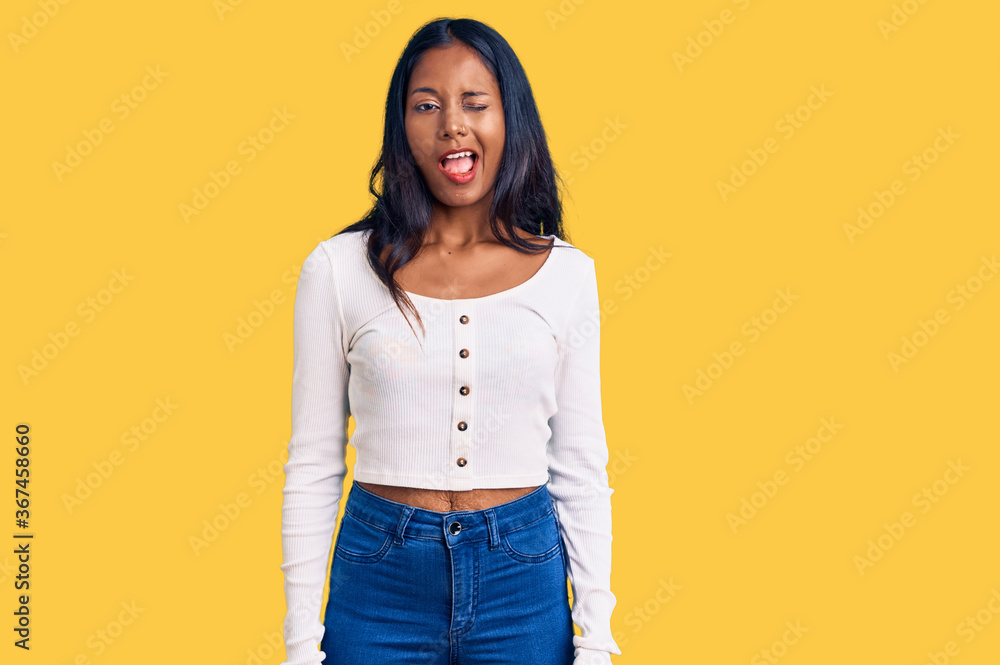 Young indian girl wearing casual clothes winking looking at the camera with sexy expression, cheerful and happy face. Young indian girl wearing casual clothes winking looking at the camera with sexy expression, cheerful and happy face.