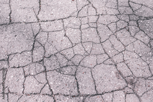 cracked asphalt surface close-up. gray old asphalt test. background ragged road top view