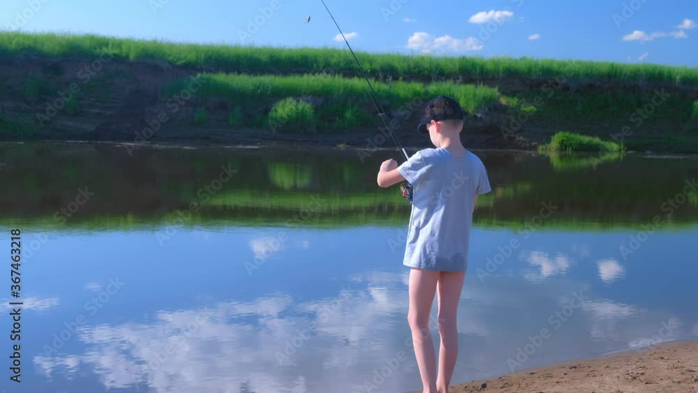 Child teen boy is fishing in river using spinning rod at summer sunny day on nature in wild beautiful place. Outdoors activity in campsite, resting in camping, Catching fish. Weekend, vacations. Child teen boy is fishing in river using spinning rod at summer sunny day on nature in wild beautiful place. Outdoors activity in campsite, resting in camping, Catching fish. Weekend, vacations.