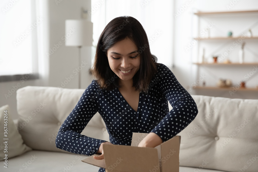 Excited millennial Asian girl sit in living room unpack cardboard box order shopping online on internet, happy young Vietnamese woman unbox carton postal package, good delivery service concept Excited millennial Asian girl sit in living room unpack cardboard box order shopping online on internet, happy young Vietnamese woman unbox carton postal package, good delivery service concept