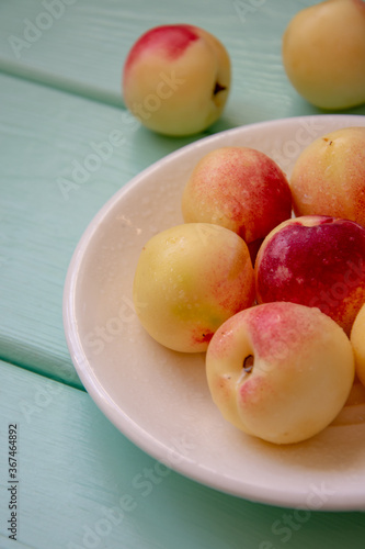 Juicy nectarines on a white plate on a light green wooden background