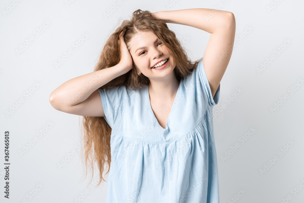 Fototapeta premium Portrait of attractive carefree european girl, tilting head up and shaking curly hair. Living life to fullest. Having fun and being amused.