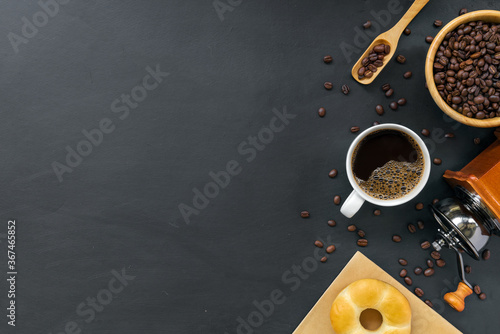 hot coffee, donuts, bean and hand grinder on black table background. space for text. top view