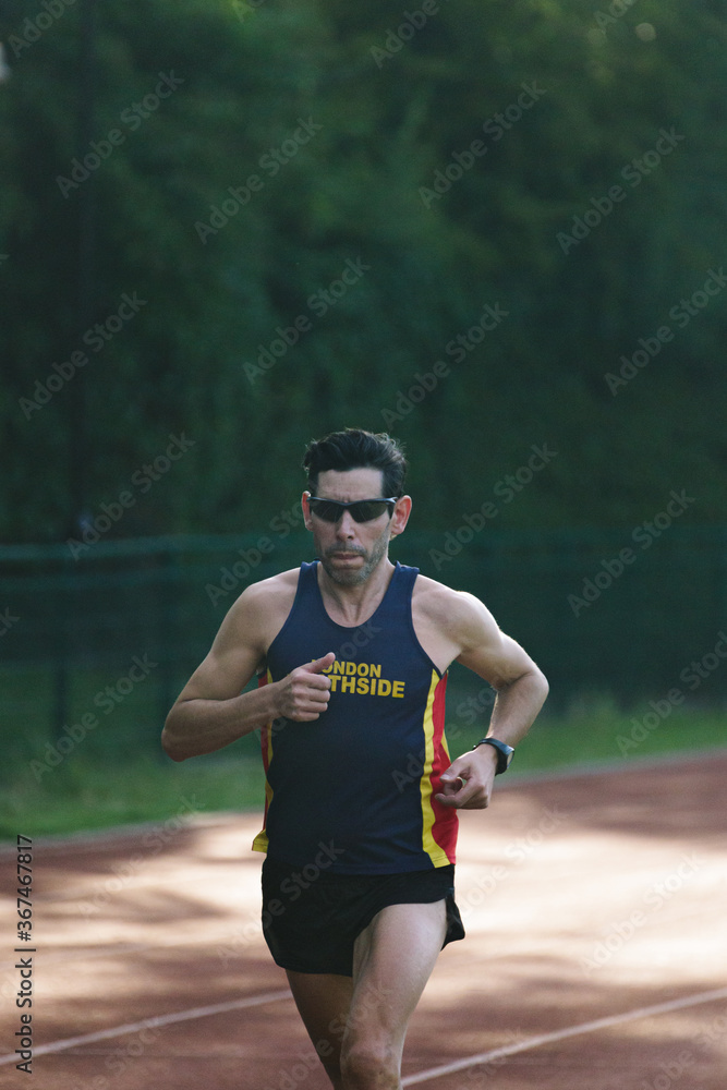 Male runner in sportswear running. Selective focus on the man and defocused background.