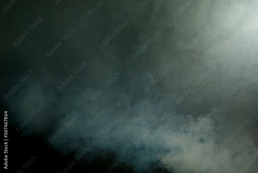 White smoke on a black background. Colored smoke with a blue and green tinge. The texture of scattered smoke. Blank for design. Layout for collages.