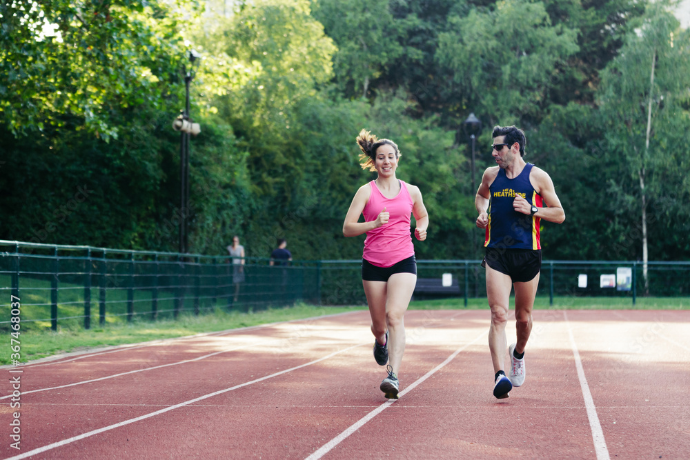 Obraz premium Active sporty woman and man in sportswear running. Selective focus on the them and defocused background.