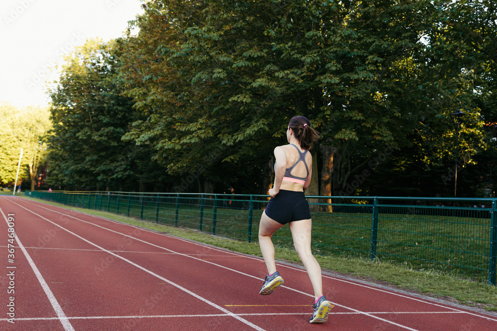 Female runner in sportswear running. Selective focus on the woman and defocused background.