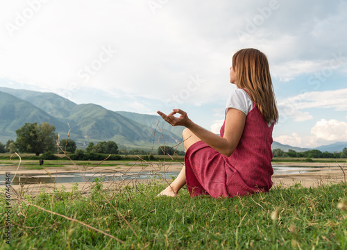 Young woman sitting at ease by the lake in silence