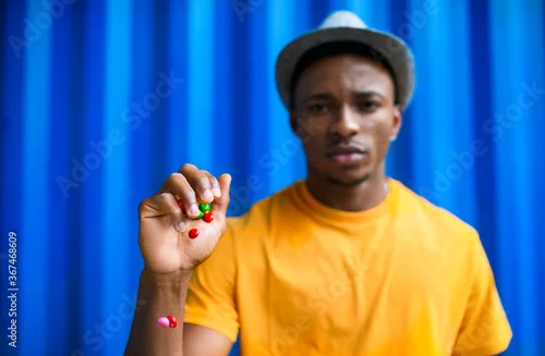 Obraz Man with skittles standing against blue background, black lives matter concept.