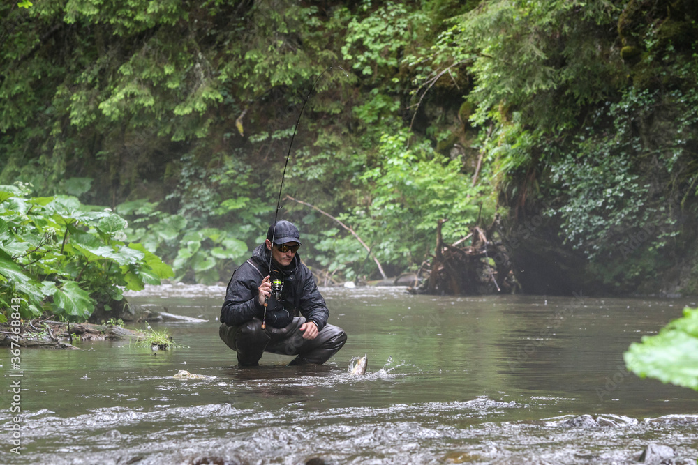 Fisherman hunting salmon fish. Outdoor fishing in river during rain. Hunting and hobby sport. Fisherman hunting salmon fish. Outdoor fishing in river during rain. Hunting and hobby sport.