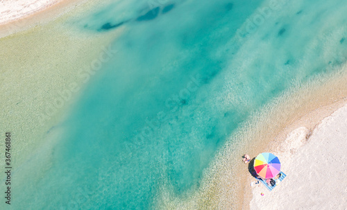 Aerial view at beautiful sea and coast with rainbow umbrella. Copy space