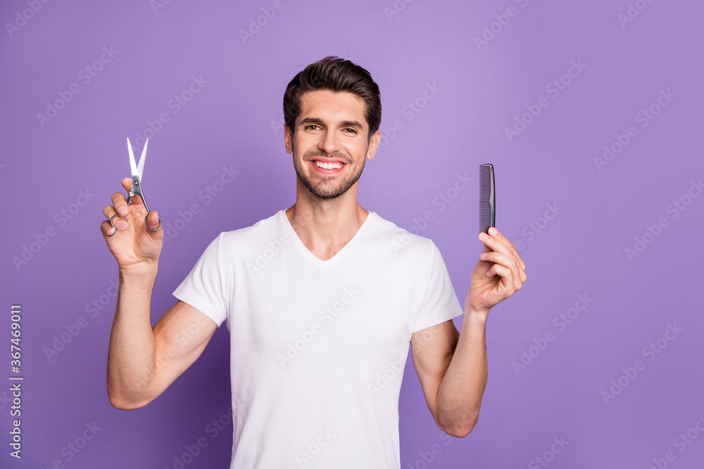 Portrait of his he nice attractive groomed cheerful brown-haired guy holding in hands comb scissors choosing solution isolated on bright vivid shine vibrant lilac violet purple color background
