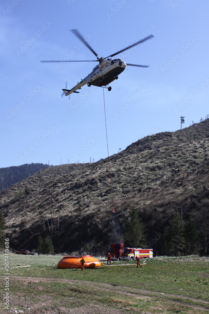 The crew of the helicopter firefighters preparing the water bag to  extinguish a large forest fire in the National Park. Stock Photo | Adobe  Stock