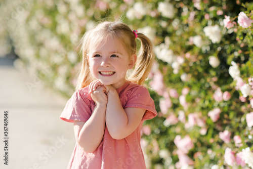 Laughing baby girl 2-3 year old posing over nature flower background closeup. Childhood. Summer season. Joyful child.