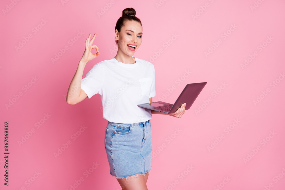 Photo of positive cheerful girl recommend work remote laptop wink blink  show okay sign wear white t-shirt denim jeans isolated over pastel color  background Stock Photo | Adobe Stock