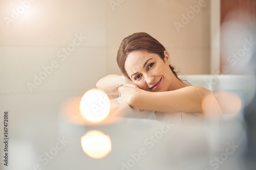Serene lady leaning on the edge of the bathtub