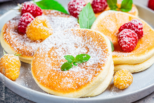 Japanese fluffy pancakes with raspberries in gray plate, gray background. Japanese cuisine concept.