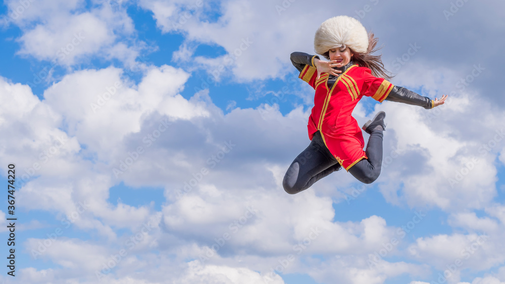 A young girl is dancing in the clouds and jumping in a national Caucasian costume (lezginka) and in a white hat. Summer Adventures. A young girl is dancing in the clouds and jumping in a national Caucasian costume (lezginka) and in a white hat. Summer Adventures.