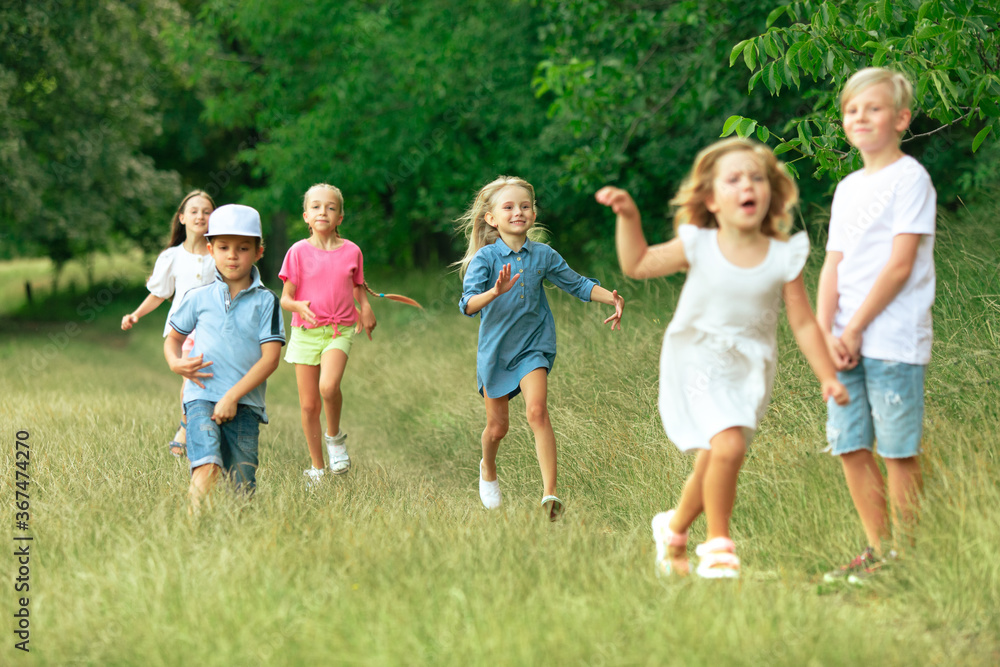 Kids, children running on meadow in summer's sunlight. Look happy, cheerful with sincere bright emotions. Cute caucasian boys and girls. Concept of childhood, happiness, movement, family and summer. Kids, children running on meadow in summer's sunlight. Look happy, cheerful with sincere bright emotions. Cute caucasian boys and girls. Concept of childhood, happiness, movement, family and summer.