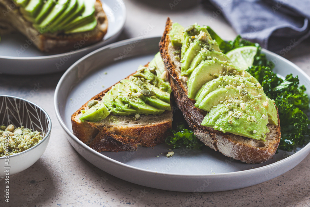 Avocado toasts with seeds on a gray plate. Plant based diet concept.