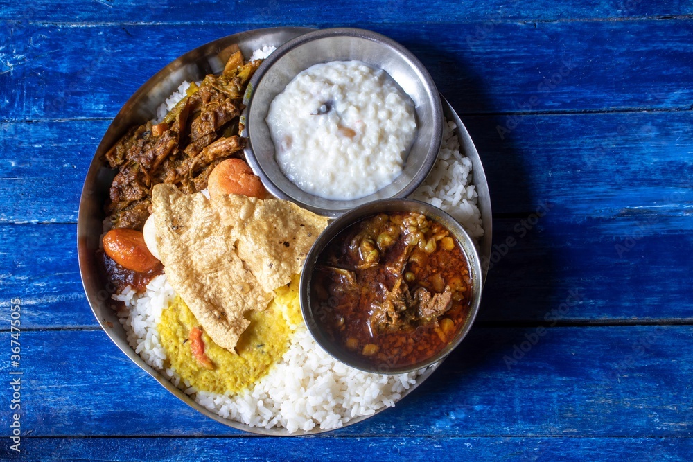 Rice with Goat Curry and Other Dishes in Steel Plate on Blue Wooden Background, Typical Bengali Food Platter or Thali Rice with Goat Curry and Other Dishes in Steel Plate on Blue Wooden Background, Typical Bengali Food Platter or Thali