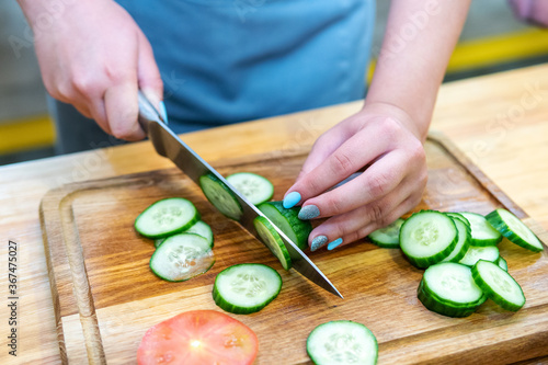 hands cut cucumber into slices