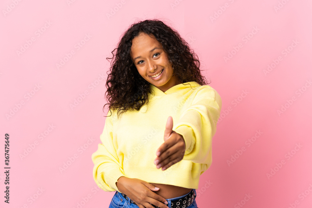 Teenager cuban girl isolated on pink background shaking hands for closing a good deal Teenager cuban girl isolated on pink background shaking hands for closing a good deal