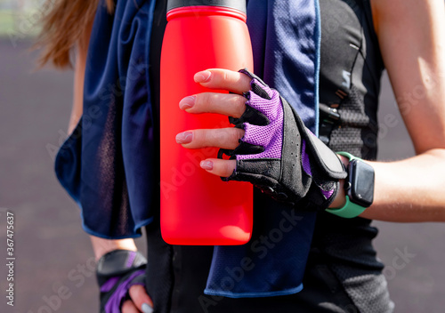 Hands of a fitness girl with a smart watch and sports equipment on the street, selective focus