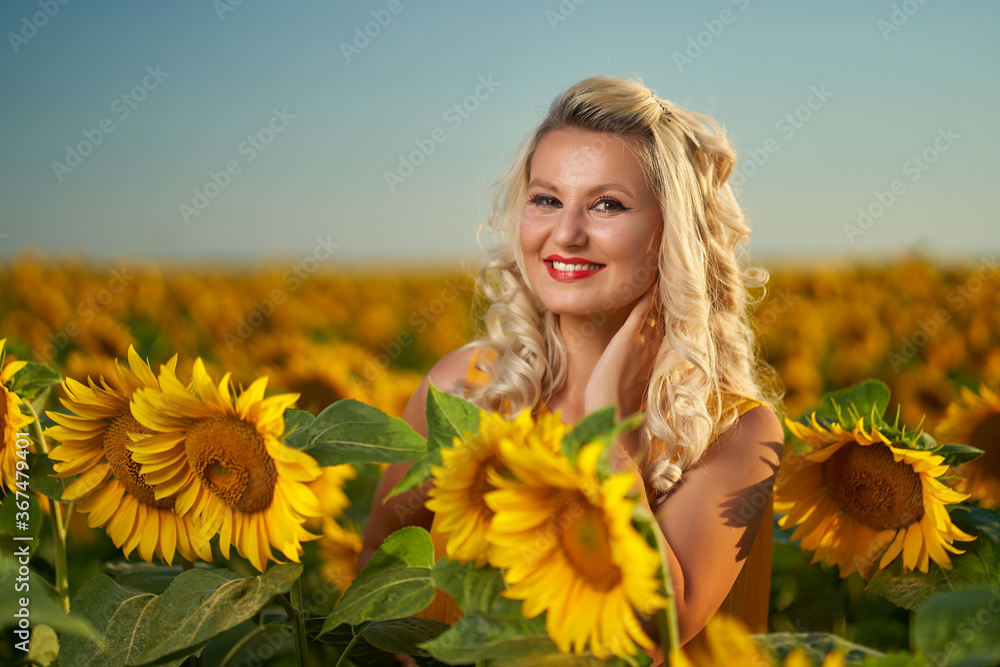Young attractive woman in a sunflower field at sunset Young attractive woman in a sunflower field at sunset